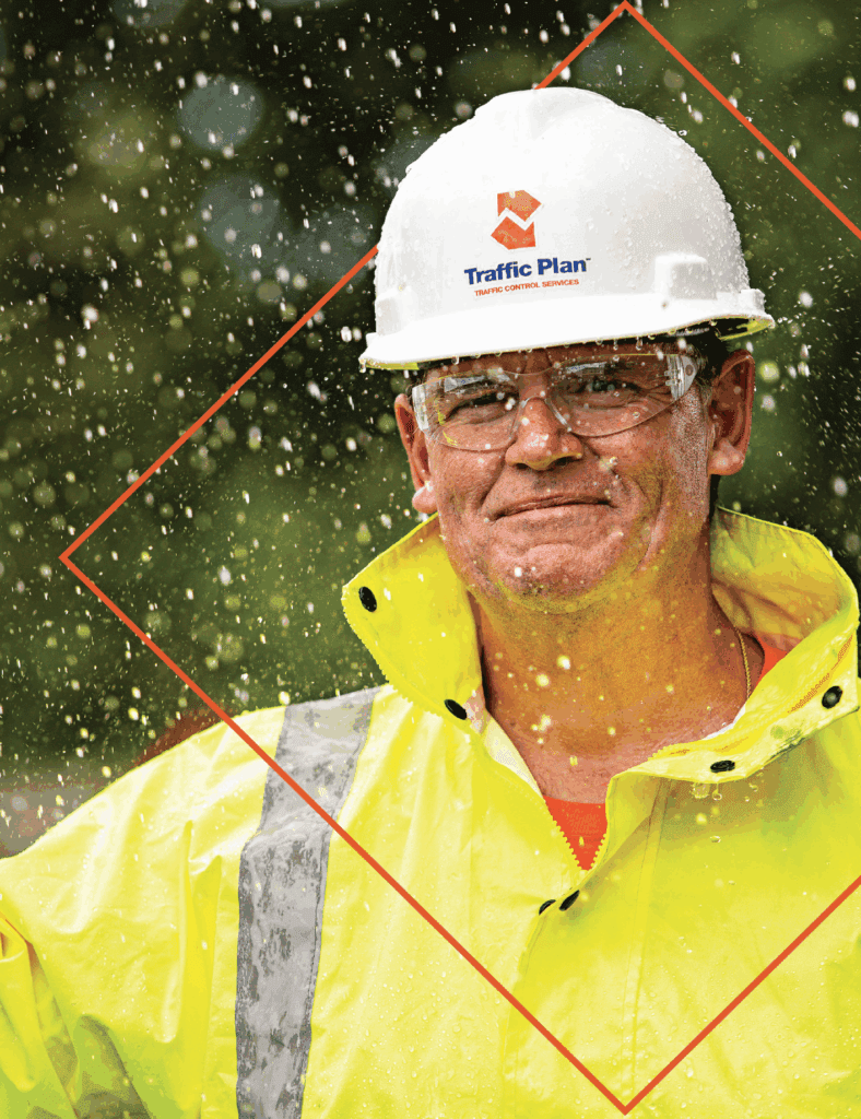 traffic plan employee standing in the rain while wearing full company garb and safety glasses