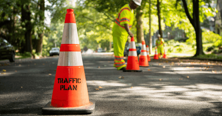 traffic plan branded orange cones sitting in straight line while crew members set up for work