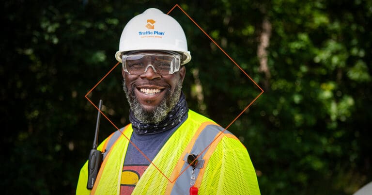 traffic plan employee smiling while wearing company branded hard hat and vest