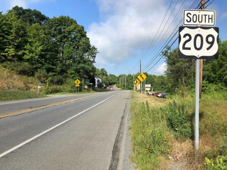 highway with south 209 sign posted on the right sitting beneath a blue sky with white clouds