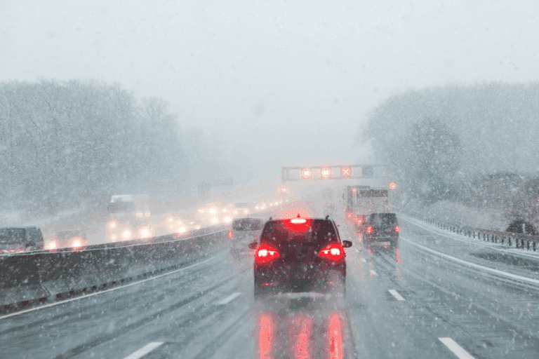 rear view of vehicle flashing its break lights on the highway surrounded by wet weather